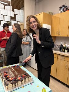 Christa cutting cake at her defense celebration